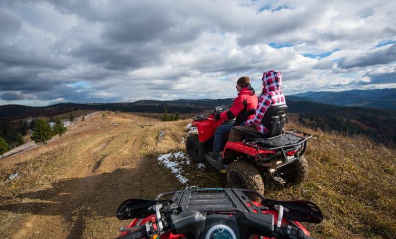 couple-driving-atv-front-top-mountain-sky-with-clouds-mountains