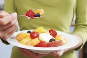 Close,Up,Of,Woman,Eating,Bowl,Of,Fresh,Fruit