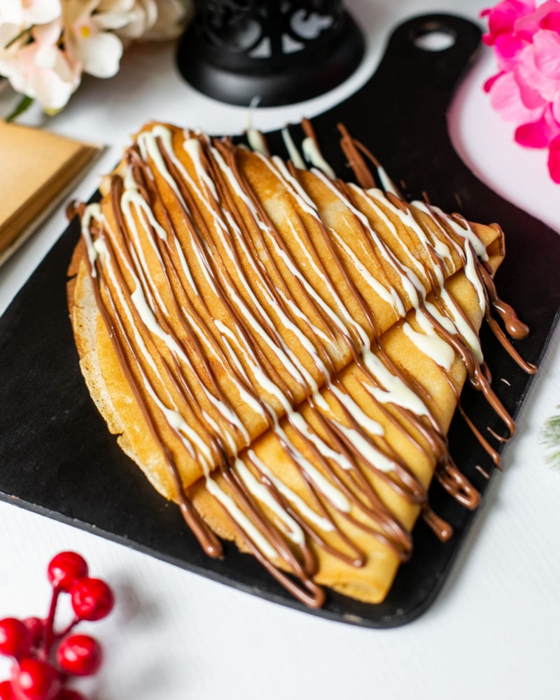 side-view-crepe-with-chocolate-cocoa-syrup-wooden-cutting-board