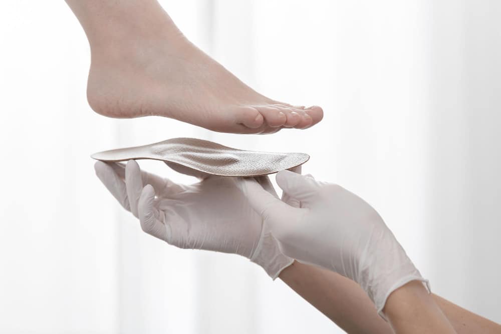 cropped-hand-doctor-holding-insoles-by-patient-feet